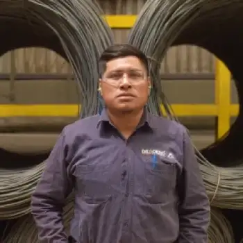 Trabajador con rollos de acero al fondo