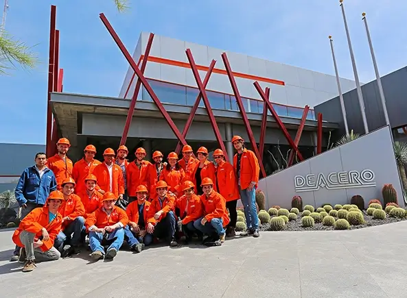 Trabajadores en frente de logo Deacero