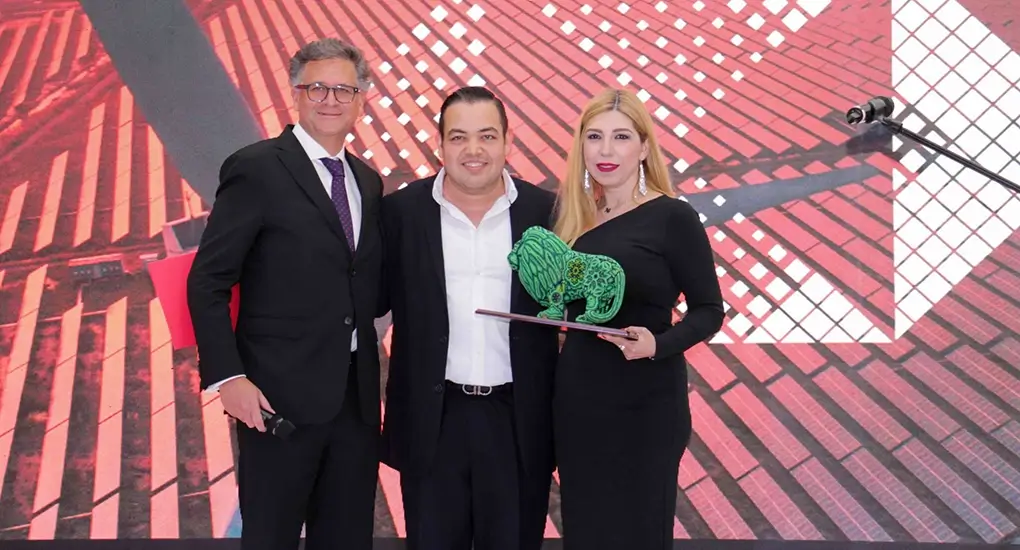 Tres personas con un premio en forma de leon
