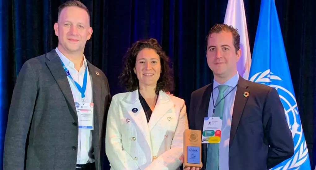 Tres personas con un premio con banderas en fondo